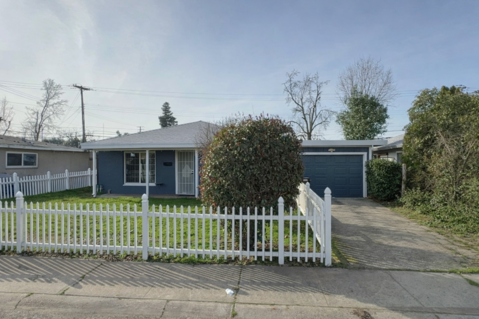 Single-story home with white fence and driveway ready for sale